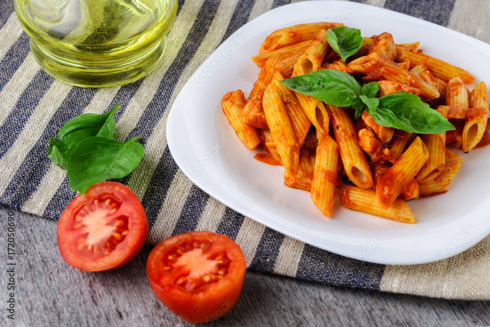 Penne with tomato sauce and basil on wooden background Penne with tomato sauce and basil on wooden background