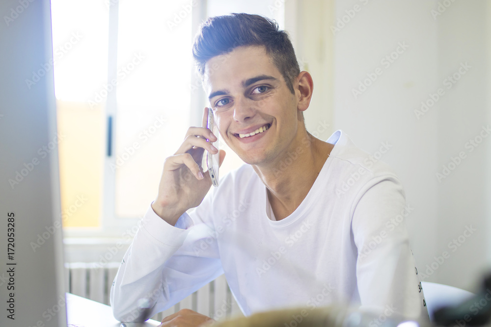 young man with mobile phone and computer studying or working on the desktop young man with mobile phone and computer studying or working on the desktop