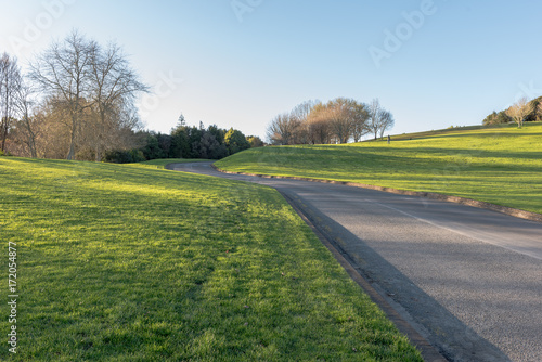 A road running through grassly land under a blue sky