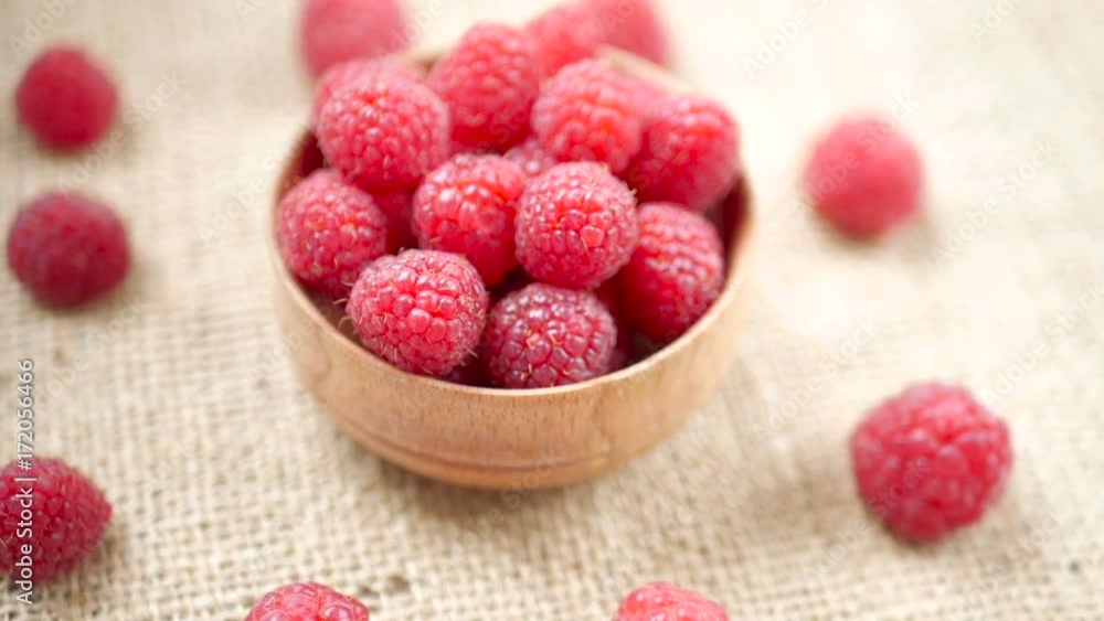 Fresh raspberry in wooden bowl rotating in sun lights on burlap background. Organic fruits for breakfast Fresh raspberry in wooden bowl rotating in sun lights on burlap background. Organic fruits for breakfast