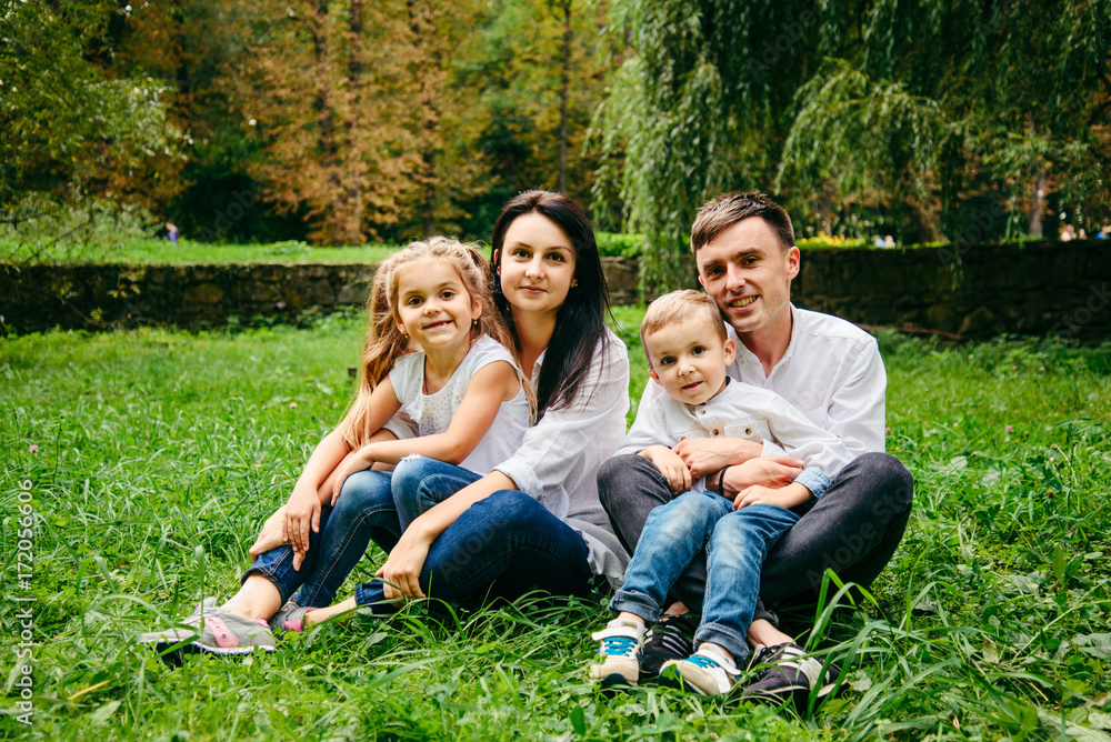 portrait of happy family mother, father, duaghter and son sit on the ground portrait of happy family mother, father, duaghter and son sit on the ground