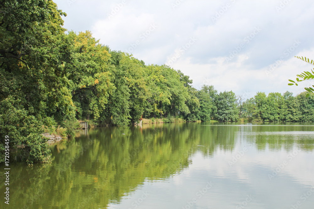 Dam on pond with trees and sky, Czech landscape.