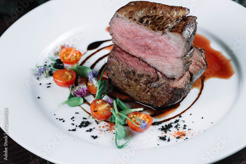 Tenderloin steak on plate with salad on dark background