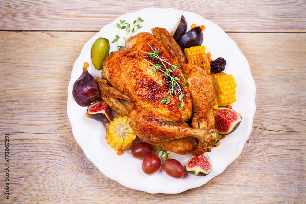 Whole chicken with fruits, vegetables and berries: figs, corn on cob, grape, plums and blackberry. View from above, top, horizontal Whole chicken with fruits, vegetables and berries: figs, corn on cob, grape, plums and blackberry. View from above, top, horizontal