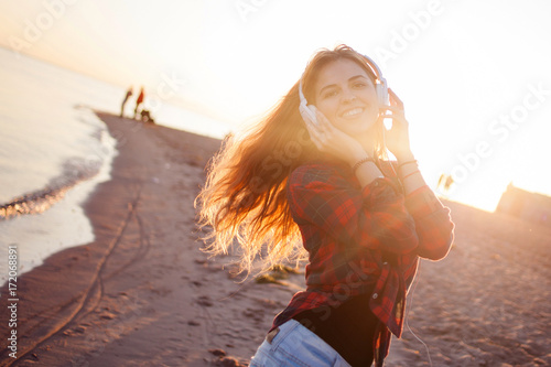 Laughing young woman enjoying the music. Portrait in bright sunset light