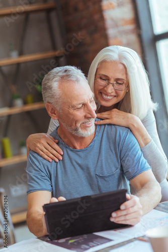 Loving aged couple using tablet at home
