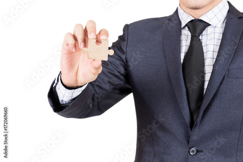Businessman holding wood jigsaw piece isolated on white background
