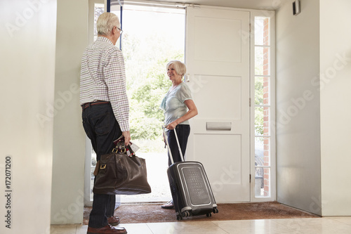 Senior couple with luggage leaving home for a holiday
