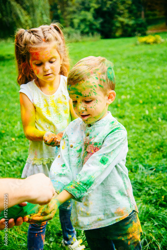 Emotional little kids playing with holi paints in city park