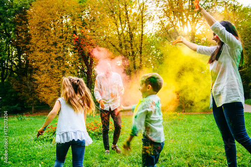 cute european family plaing with holi paints in the park