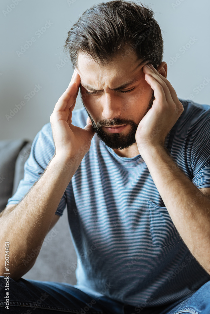 Depressed good looking man holding his temples Depressed good looking man holding his temples