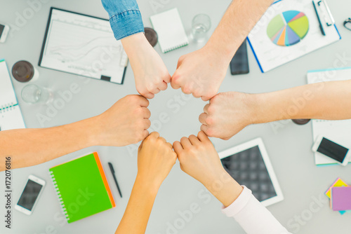 The six people hold fists at the table. view from above © realstock1