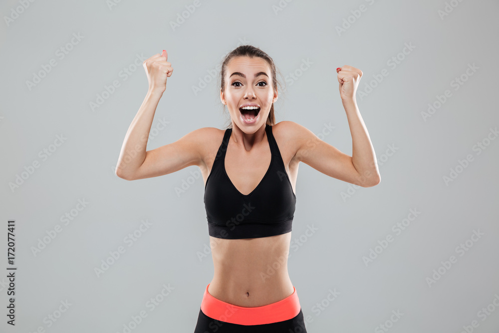 Happy cheerful sportswoman celebrating success with arms raised Happy cheerful sportswoman celebrating success with arms raised