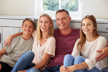 Portrait Of Smiling Family Relaxing On Seat At Home