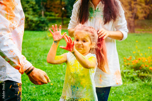 father mother and daughter full around with holi paints