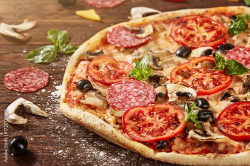 Fresh pizza with tomatoes, cheese and mushrooms on wooden table