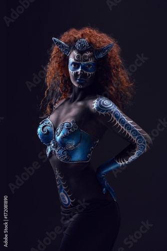 Fabulous female from fairytale with blue black body art, corset and horns