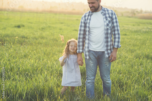 father and daughter walking in high grass field