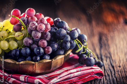 Grape. Bunch of multicolored grapes in retro bowl on old oak table