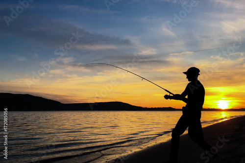 Young man fishing at sunset
