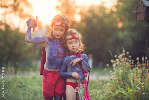Happy children play superheroes at sunset in the backyard. Party with dressing. Children on the street during Halloween. The concept of childhood.