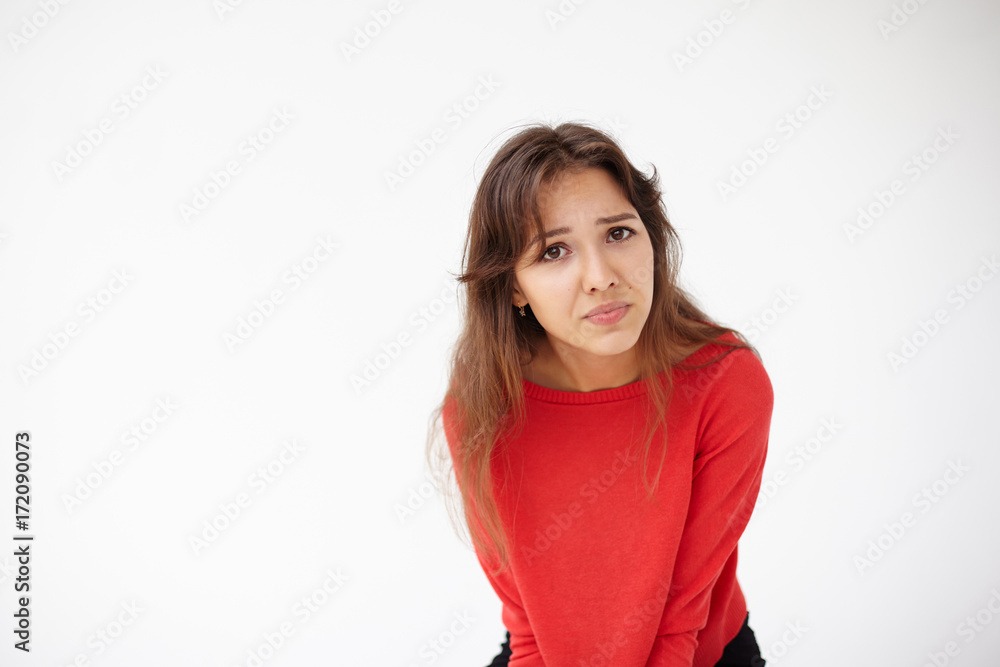 Picture of brunette Hispanic female in red sweater leaning forward, frowning. Irritated woman making grimace and staring at camera, having indignant, displeased or annoyed facial expression Picture of brunette Hispanic female in red sweater leaning forward, frowning. Irritated woman making grimace and staring at camera, having indignant, displeased or annoyed facial expression