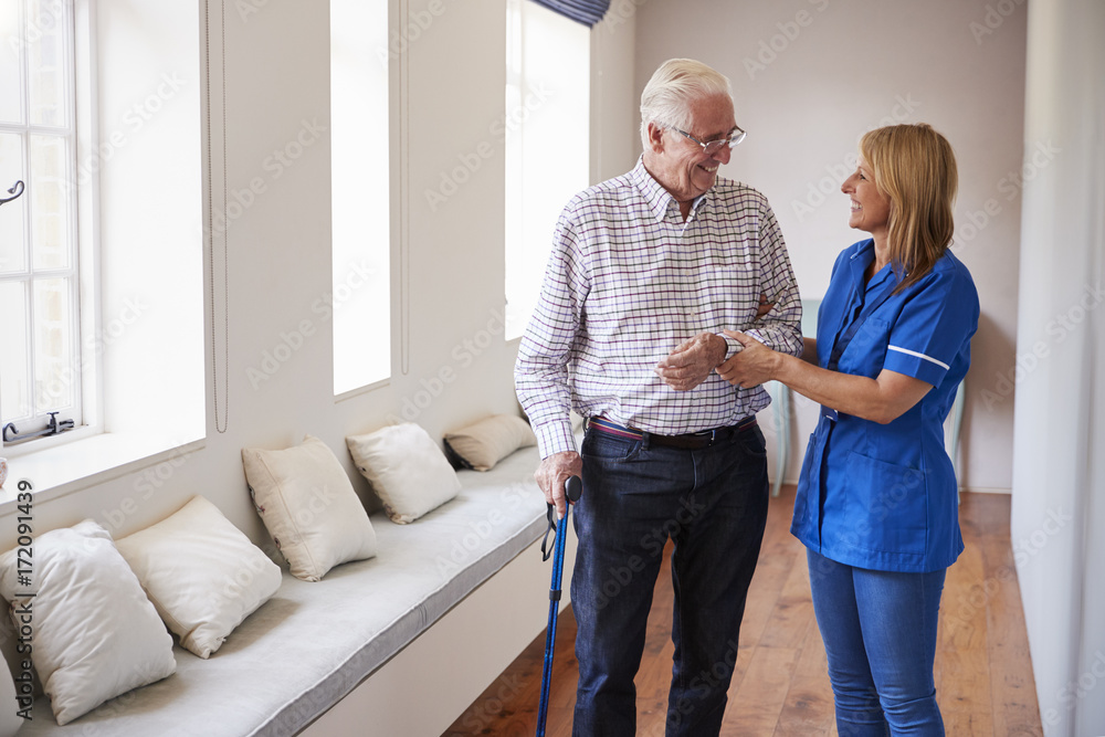 Obraz premium Nurse helping senior man walk using a walking stick
