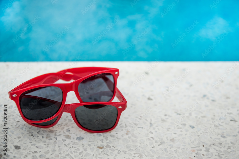 Two red sunglasses at swimming pool. Copy Space