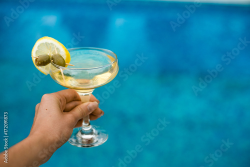 Photography Bright martini cocktail on the pool background in hand