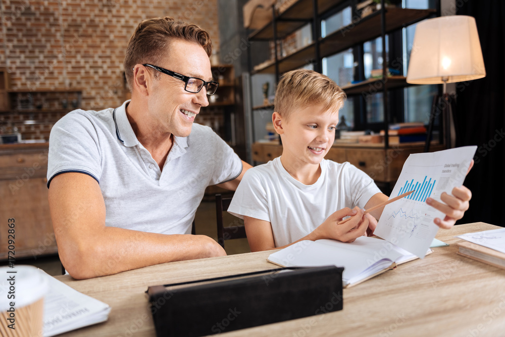 Pleasant boy describing charts to his father Pleasant boy describing charts to his father