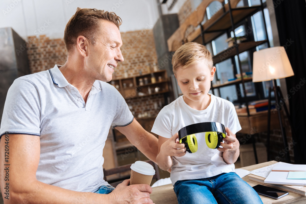 Little boy sitting near father and looking at headphones Little boy sitting near father and looking at headphones