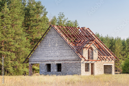 Unfinished house of foamed concrete with metal roof construction at countryside near forest