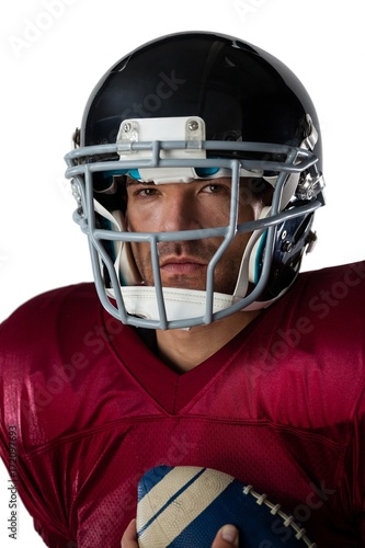 Portrait of American football player wearing helmet holding ball