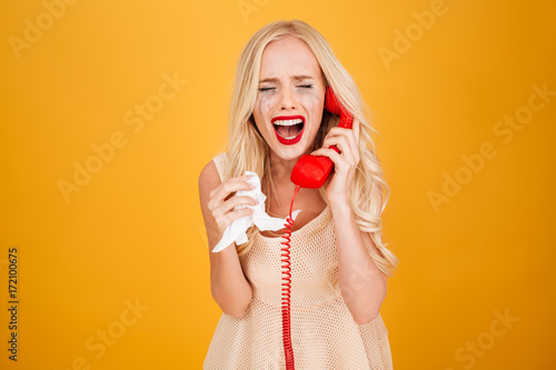 Billede på lærred Sad crying screaming young blonde woman talking by telephone.