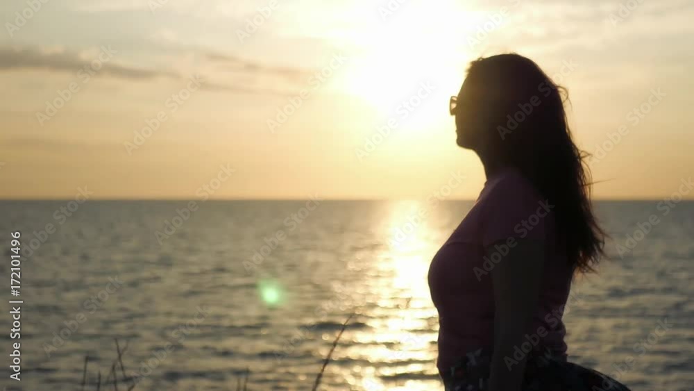 A young girl admires the beautiful sunset by the sea, a light wind blows. 4k, 3840x2160. HD A young girl admires the beautiful sunset by the sea, a light wind blows. 4k, 3840x2160. HD