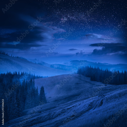 Mountain valley with blue clouds in a moonlight