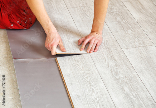 handyman's hands laying down laminate flooring boards