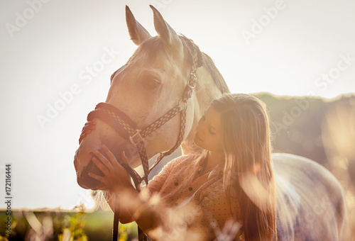 Woman hugging her horse at sunset, autumn scene
