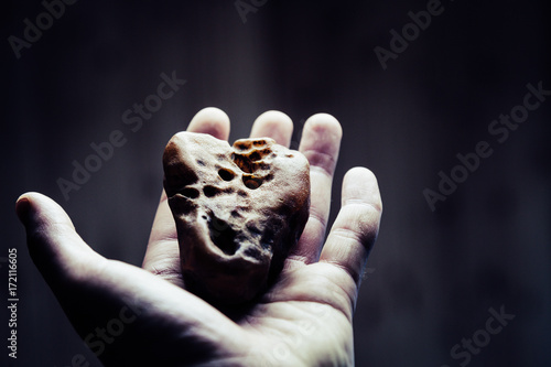 Hand holds amber. Sun stone in hand on the white background. Person shows amber in a hand. Ancient resin with insects. Amber on the palm. Semiprecious stone photo