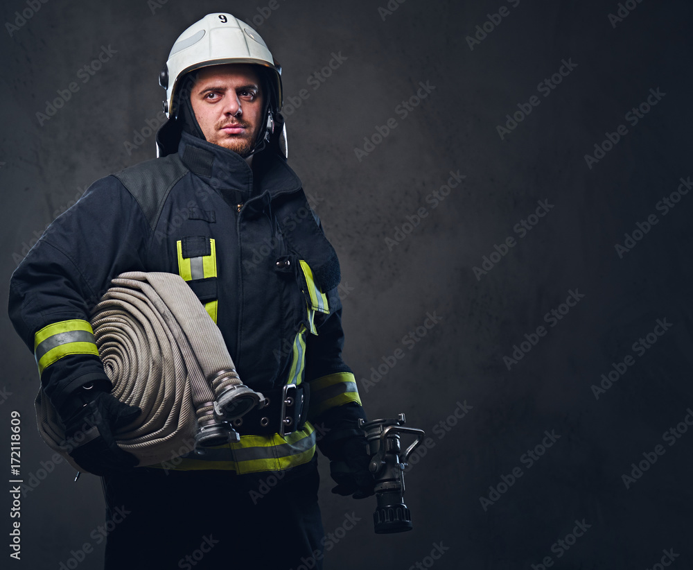Fototapeta premium Firefighter in uniform holds fire hose.