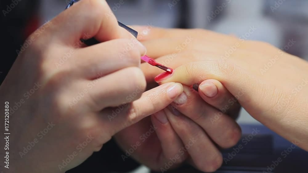 manicure making female hands, covering of transparent enamel and red nail varnish, nail polish.Woman hands in a nail salon receiving a manicure by a beautician. Woman getting nail manicure. manicure making female hands, covering of transparent enamel and red nail varnish, nail polish.Woman hands in a nail salon receiving a manicure by a beautician. Woman getting nail manicure.