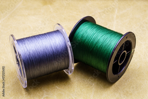 Spools of cords on the background of tarpaulin. Green and gray fishing line. Spools of braided fishing line