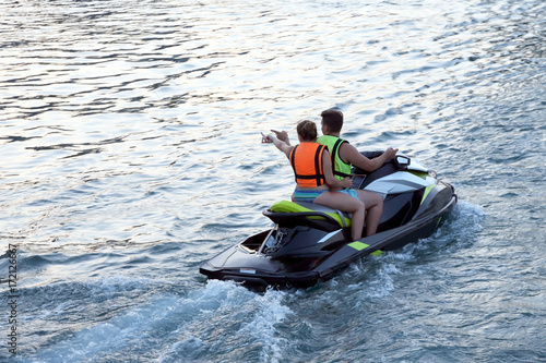 man and woman ride on a water scooter.