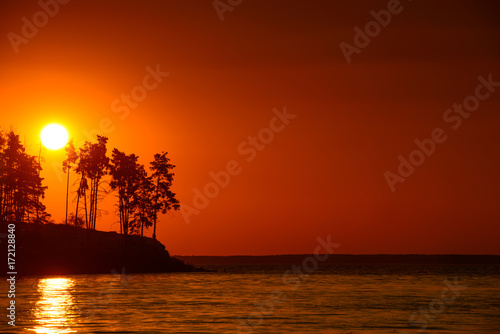 Beautiful sunset on the lake with cliff and pine trees