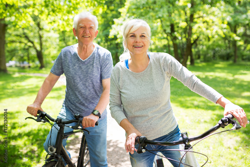 Obraz premium Senior Couple Riding Bikes In Park