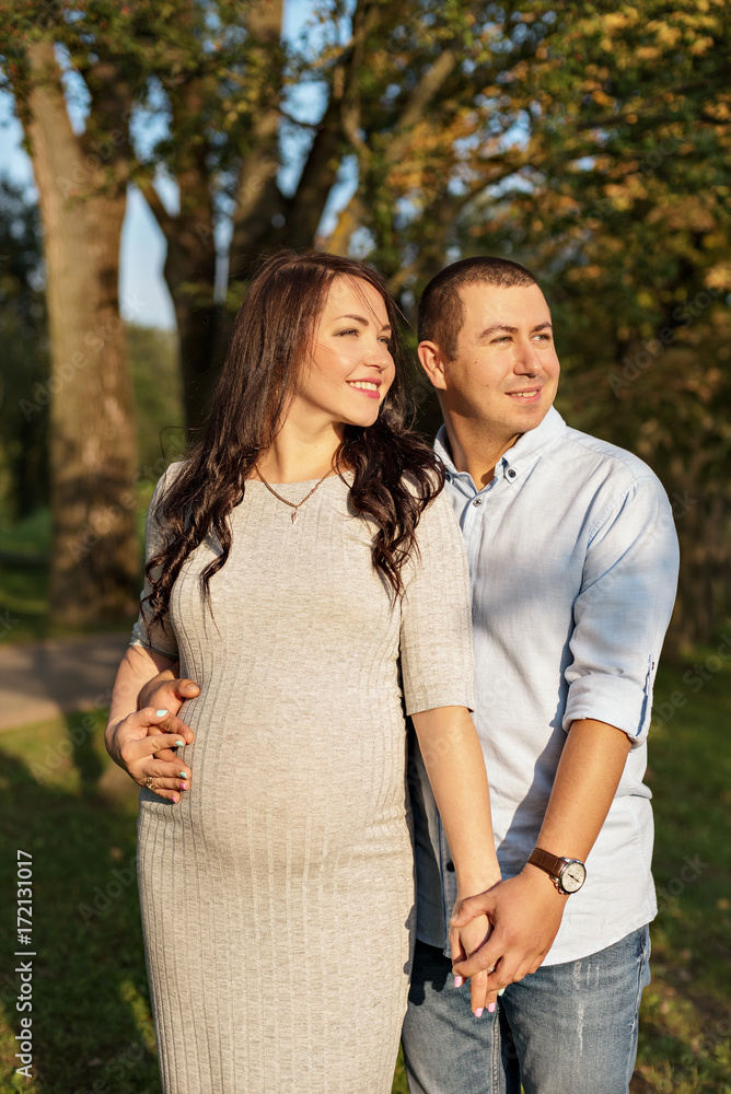Fototapeta premium couple family in the expectation of a baby hugging in the city in sun rays