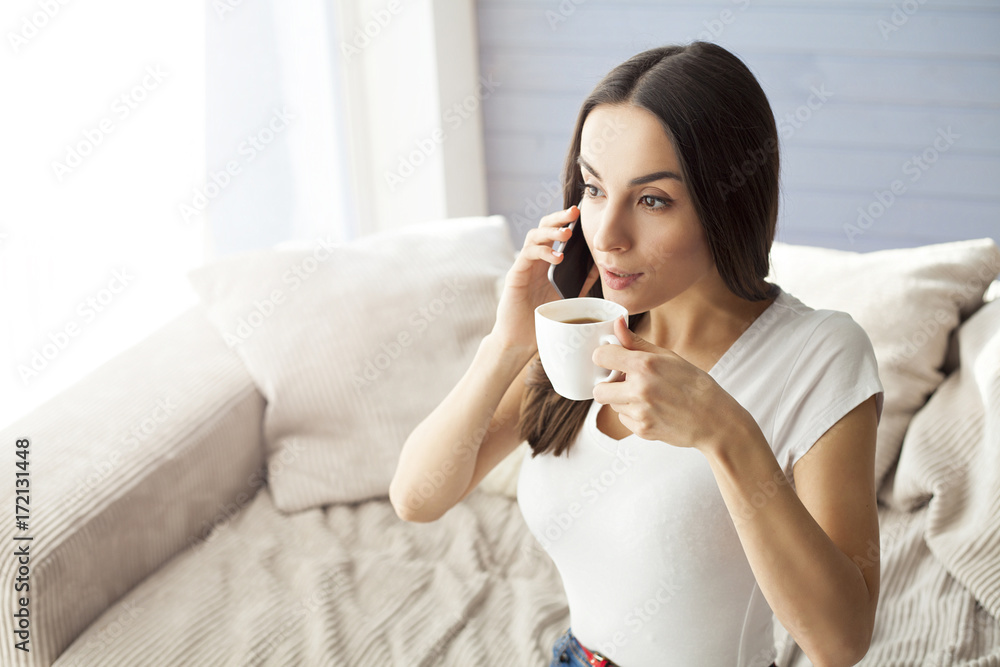 Beautiful young girl speaks by phone on a sofa at home. Beautiful young girl speaks by phone on a sofa at home.