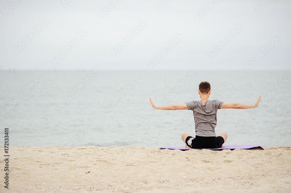 man practicing yoga on the beach in the early morning. man practicing yoga on the beach in the early morning.