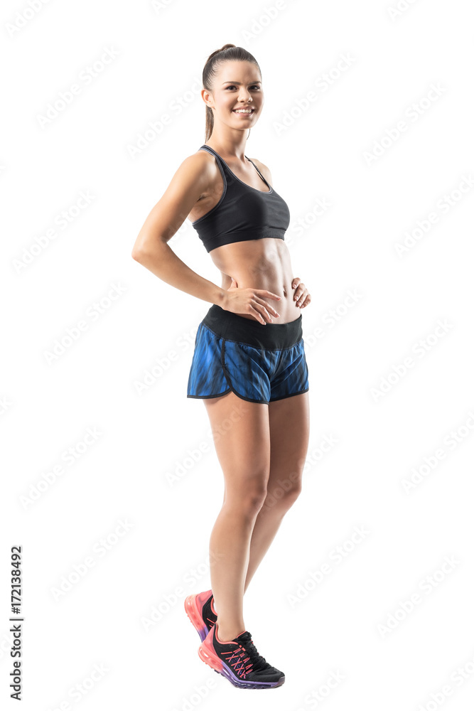 Excited cheerful fit gym woman in sportswear posing and smiling at camera. Full body length portrait isolated on white studio background. Excited cheerful fit gym woman in sportswear posing and smiling at camera. Full body length portrait isolated on white studio background.