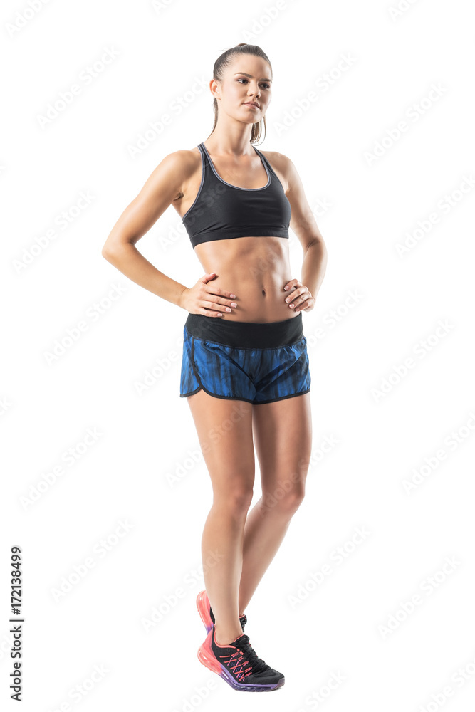 Confident fitness sporty woman with hands on hips looking away. Full body length portrait isolated on white studio background. Confident fitness sporty woman with hands on hips looking away. Full body length portrait isolated on white studio background.